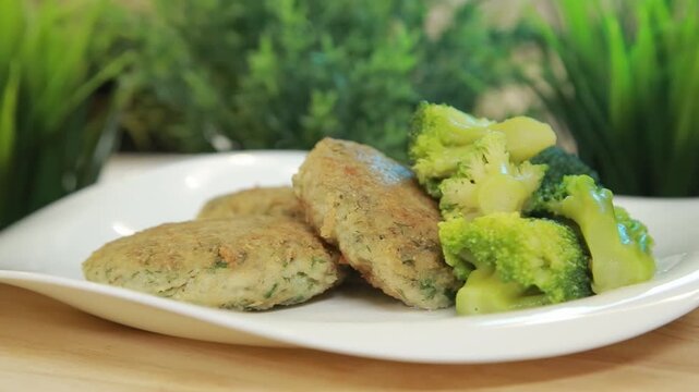 Homemade fish patties served with steamed broccoli on a white ceramic plate