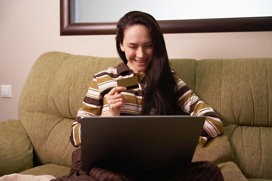 Woman shopping online at home with a laptop and card