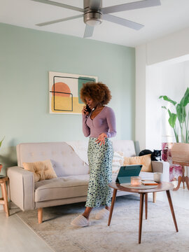 Woman talking on phone while walking at home 