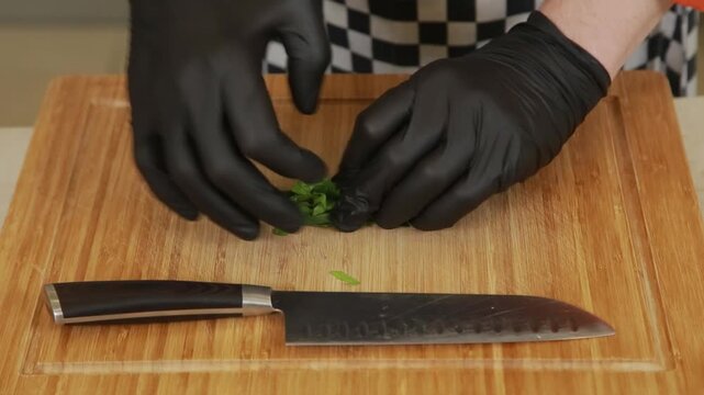 Chef finely chops fresh herbs on a wooden cutting board