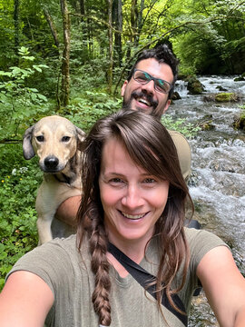 Couple Takes a Selfie With Dog by a Stream in the Woods