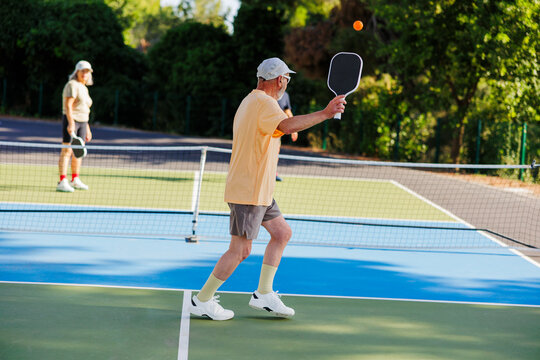 Senior friends enjoying pickleball game on outdoor court