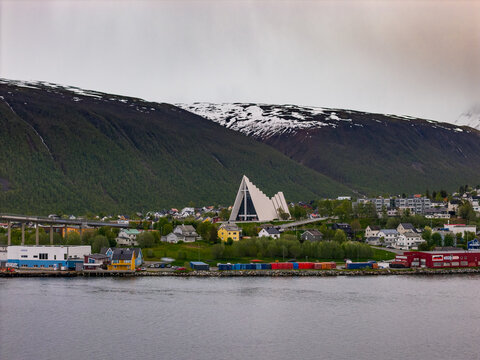 Aerial view of the Arctic Cathedral with its distinctive triangular architecture set against snowy mountains and the waterfront in Tromsdalen, Troms, Norway.