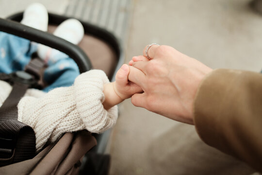 Closeup crop photo of anonymous mother holding her baby&rsquo;s tiny hand