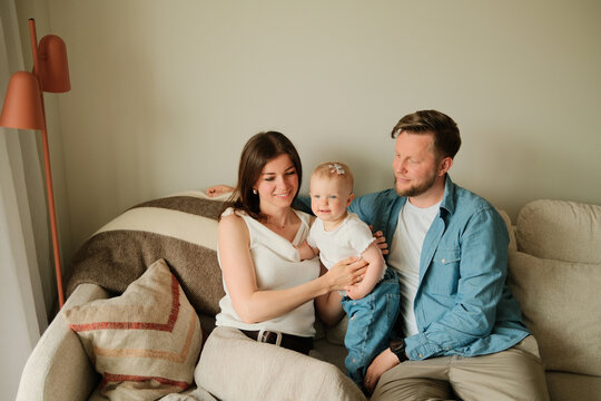 Indoors portrait of happy parents and their child at home on the couch