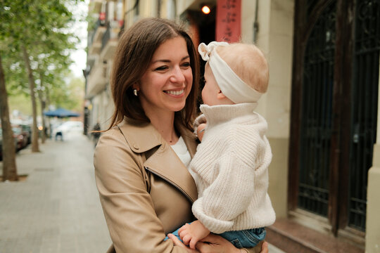 Portrait of happy mother holding her baby daughter in the street 