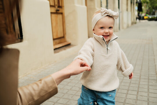 Anonymous mother holding her baby girl by the hand in the street 