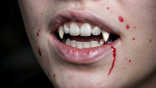 Vampire mouth with sharp fangs. Close up of bloody lips for horror and Halloween themes.