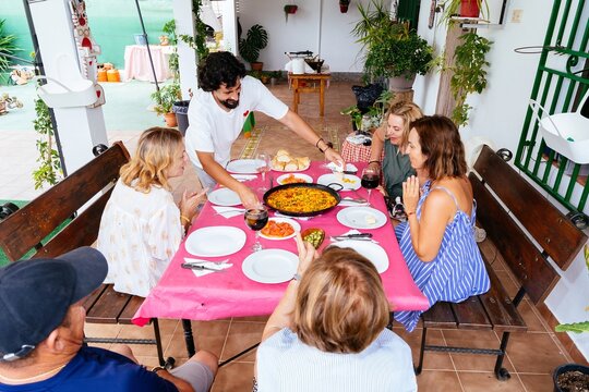 Group of friends sharing paella lunch on outdoor terrace