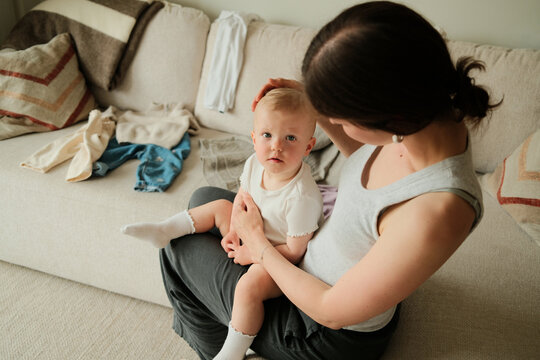 Portrait of mother cuddling and patting her child at home 