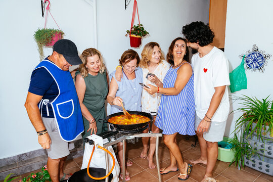 Family cooking paella together on an outdoor terrace