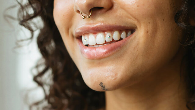 Close up of woman smiling with tooth gems. Portrait of person with septum piercing.
