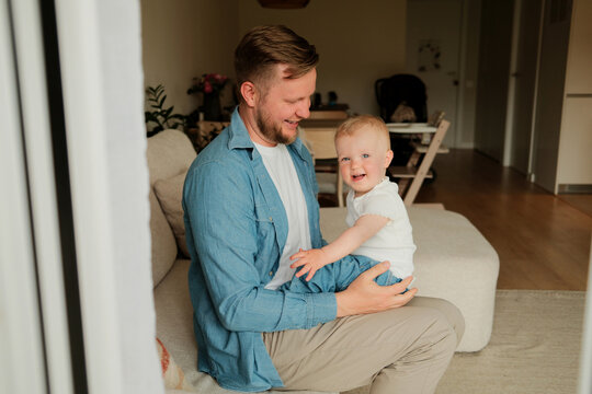 Happy smiling father looking at his little laughing baby girl at home 