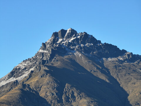Aerial view of the rugged, snow-dusted peak of a mountain near Glenorchy, Otago Region, New Zealand.