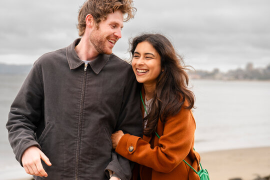 candid looving couple walk together smiling arm in arm  