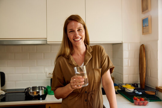 Happy woman drinks water at home