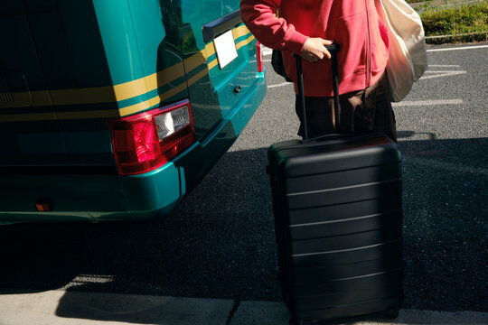 Man Pulling Suitcase Beside Tour Bus