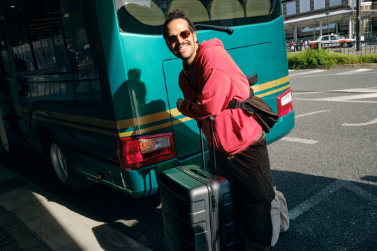 Man with Suitcase Beside Tour Bus