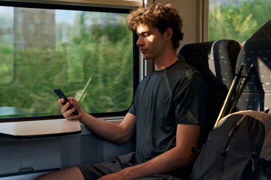 Young Man Using Phone While Sitting on Train