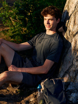 Man Rests Under a Tree During Outdoor Activity in the Evening