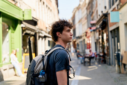 Young Man Walking in a City Street With Backpack and Sunglasses