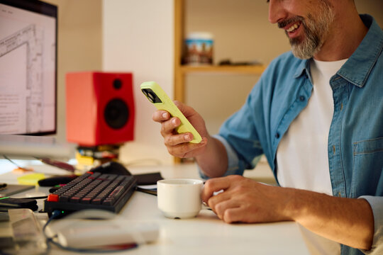 Man Checks Phone While Working at Desk