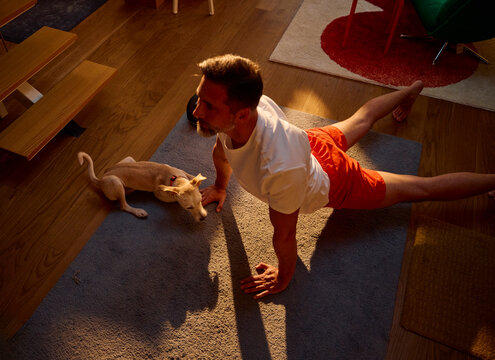 An active man stretching his back with a dog by his side.