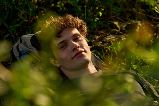 Young Man Resting Outdoors With Greenery Around Him