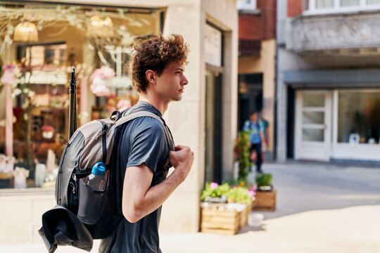 Young Man Walks on Street With Backpack in Urban Setting