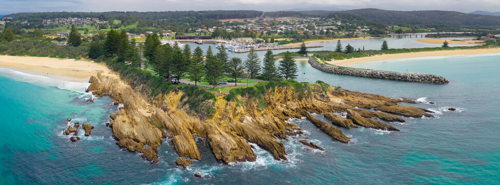 Coastal parkland above a rocky headland jutting out into a blue ocean