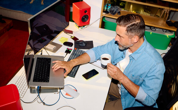 Man works at a desk in the home office, drinking coffee