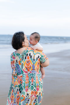 Mother and baby sharing a tender moment on a sandy beach