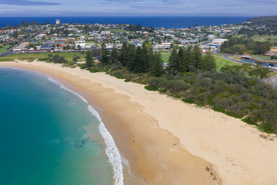 Deserted sandy beach and a calm blue sea in front of a coastal town