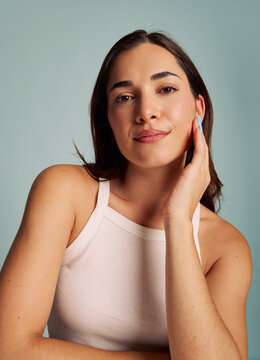 Woman Poses With Hand on Chin in Front of Blue Background