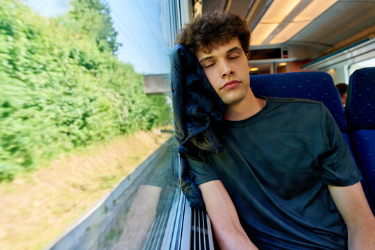 Young Man Rests on Window During Train Journey in Summer