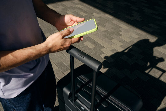 Hands Holding Phone Beside Suitcase