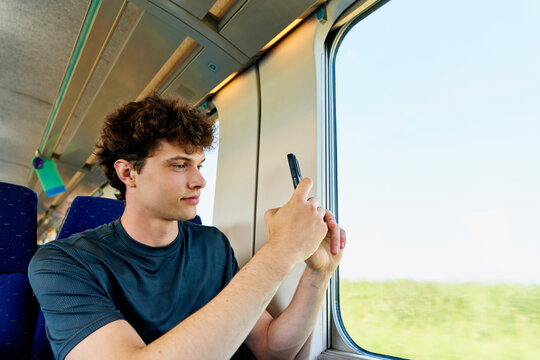 Young Man Takes Photo While Sitting in Train