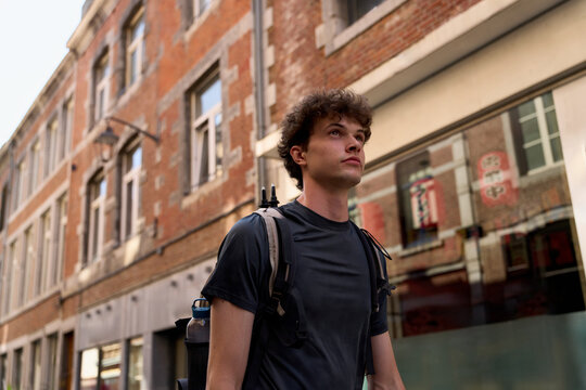 Young Man Walks in a City Street With a Backpack in the Afternoon