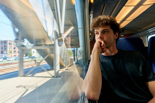 Young Man Looking out of Train Window During Travel