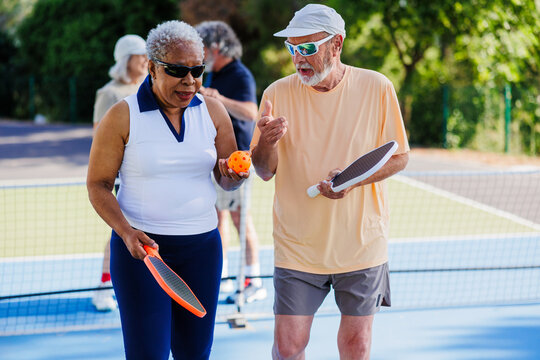 Seniors enjoying pickleball game, sharing friendly conversation