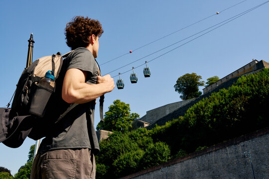 Hiker Looks up at Cable Cars While Exploring a City