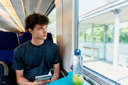 Young Person Reading a Book While Sitting on a Train