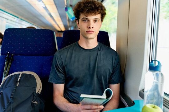 Young Man Reading a Book in a Train During the Day