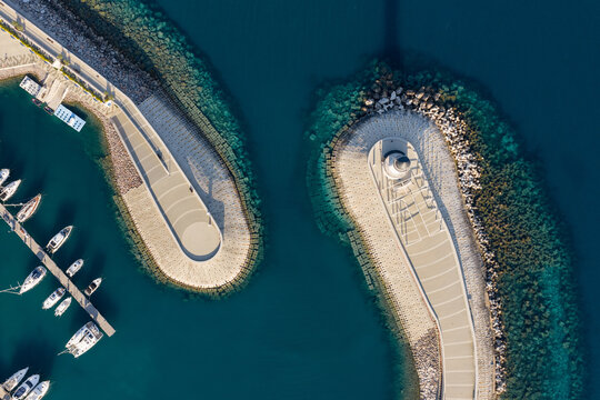 Aerial top-down view of breakwaters with lighthouse at marina entrance