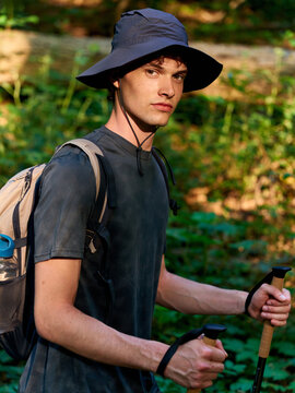 Young Man Hiking in the Forest While Holding Trekking Poles