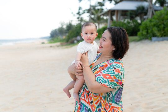 Mother holding her baby on a sandy beach
