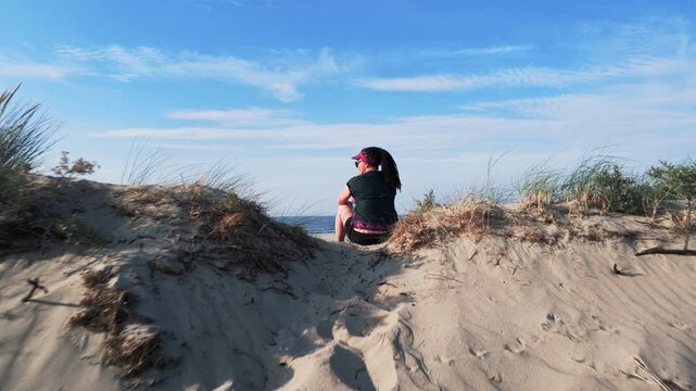 Woman sitting beside her bicycle looking out at the sea

