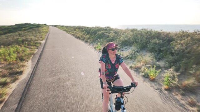 Cyclist riding toward the sea on a Dutch coastal path

