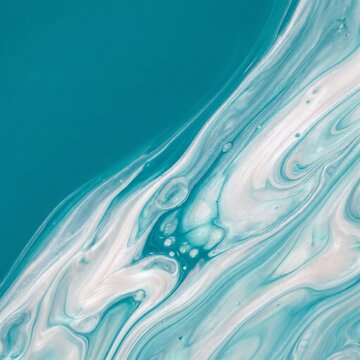 Paint waves blend blue and white tones to form a smooth artistic liquid composition on a canvas.