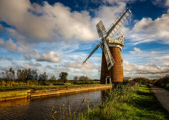 Fototapeta premium Horsey Windpump beside Norfolk Broads waterway beneath a dramatic autumn sky